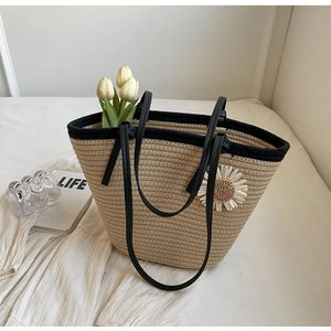 Fashionable beige woven straw tote bag with black handles and white daisy applique decor