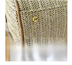 Détail de la base en paille tressée avec quatre pieds en métal doré et bordure en cuir brun