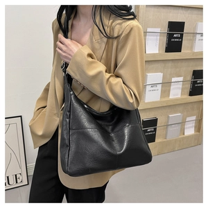 Close-up of black PU leather shoulder bag featuring pleated texture and metal buckle detail