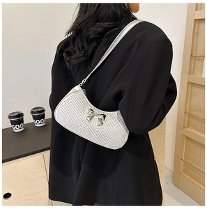 Chic silver rhinestone hobo bag featuring a metal bow detail, worn as a crossbody shoulder bag