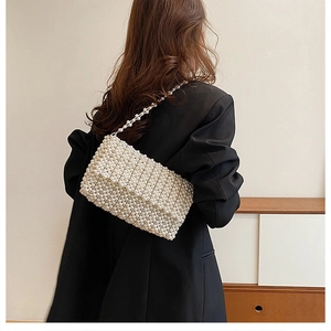 Fashionable pearl-woven crossbody bag styled on a black blazer with elegant pearl strap