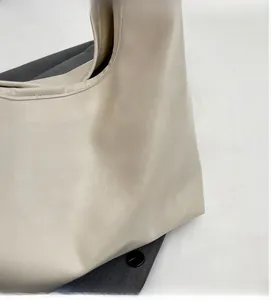 Close-up of cream PU leather handbag detail with soft pleated texture and gold logo tag