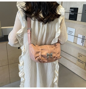 Detail of pink pleated PU crossbody bag with decorative bows and silver hardware accents