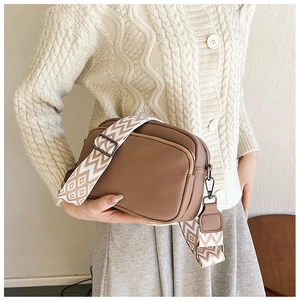 Détail du sac bandoulière en cuir grainé marron avec large sangle en jacquard tissé