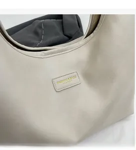 Close-up of beige PU leather shoulder bag showing fine texture and golden metal brand tag