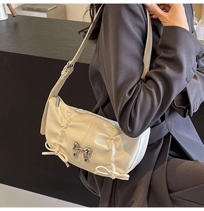Detailed view of the cream PU leather handbag with elegant pleats and silver bow accents