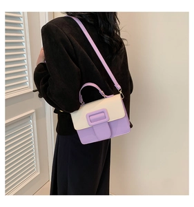 Detailed back view of purple contrast square bag worn by a model in a dark coat