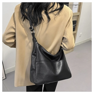 Detail view of large black textured PU crossbody bag worn with a khaki blazer