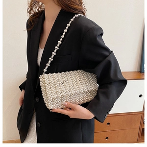 Detail view of handmade pearl woven handbag with glossy finish on a black suit blazer