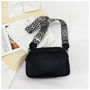 Détail du sac bandoulière noir en cuir grainé avec sangle tissée et fermeture éclair métal