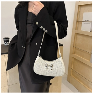 Detail of white rhinestone hobo bag with silver bow decoration worn by a model