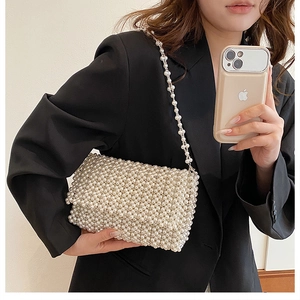 Detail of handmade cream pearl beaded handbag with elegant woven texture and long chain strap