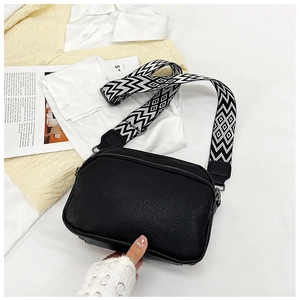 Détail du sac carré en cuir grainé noir avec bandoulière géométrique et fermeture éclair