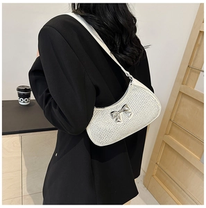 Close-up of a white rhinestone crescent bag featuring a silver metal butterfly bow detail