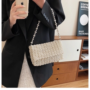 Detailed view of the elegant white faux pearl woven handbag held by a fashion model