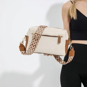 Sac bandoulière bicolore en similicuir avec large sangle jacquard porté par un mannequin