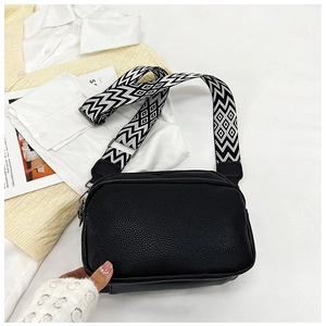 Détail du sac bandoulière en cuir grainé noir avec une sangle à motif géométrique
