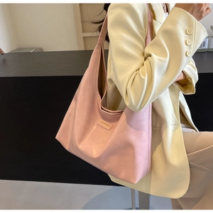 Lifestyle shot of large pink PU leather tote bag worn by model in a stylish beige suit