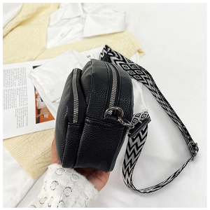 Détail du sac à bandoulière noir grainé avec double fermeture éclair et sangle géométrique