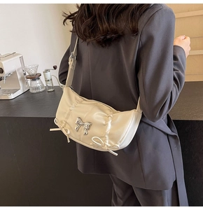 Detail of cream white PU shoulder bag with silver metal bow and satin ribbon accents