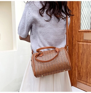 Détail du sac Boston tissé marron avec anses en cuir et rivets de fond métalliques