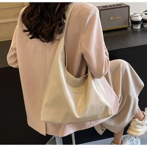 Close-up of beige matte PU leather tote bag with fashion logo detail on shoulder