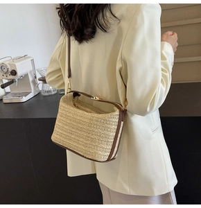 Dettaglio della borsa a secchiello in paglia beige con finiture in pelle marrone