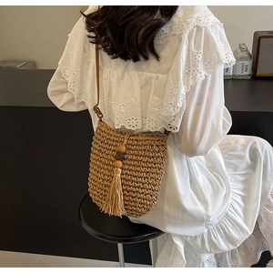 Detail der gewebten Strohtasche mit langen Fransen und Holzperlen im Boho-Stil