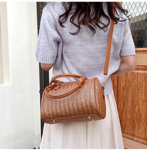 Détail du sac bandoulière marron avec texture tressée et pieds de protection dorés