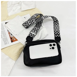 Détail du sac bandoulière noir grainé avec une large sangle à motifs géométriques