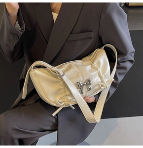 Close-up of cream PU leather shoulder bag with silver metal bow and drawstring detail