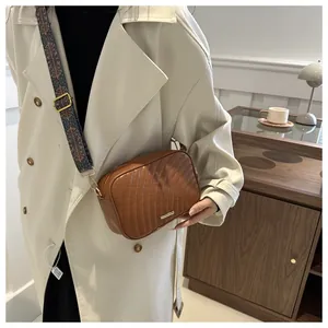 Close-up of brown quilted leather crossbody bag with vintage patterned wide strap