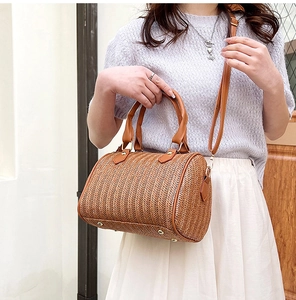 Détail de la texture en paille tissée et poignée en cuir marron sur un sac bandoulière