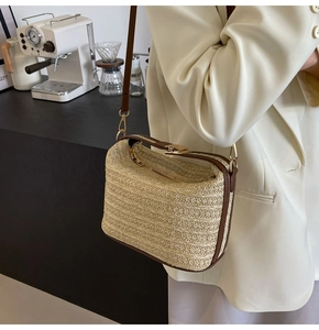 Dettaglio della borsa a tracolla in paglia con finiture in pelle marrone e zip dorate