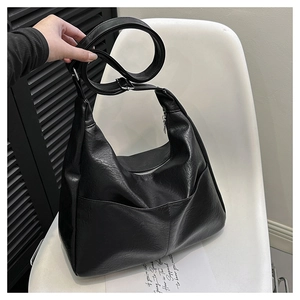 Chic black PU leather crossbody bag with adjustable strap on a white chair