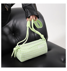 Détail du sac cylindrique à carreaux vert clair avec bandoulière à nœud en corde épais