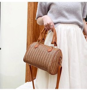 Détail d'un sac seau tressé marron avec anses en similicuir et finitions en métal doré