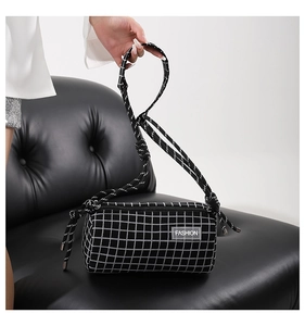 Détail du sac cylindrique en nylon à carreaux avec sangle tissée et étiquette mode