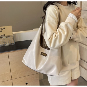 Detail of off-white PU leather tote bag featuring a brown embossed leather fashion tag