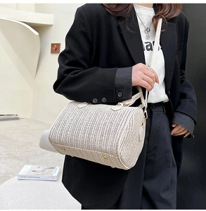 Vue détaillée du sac tonneau tressé avec pieds de protection dorés et garniture en cuir