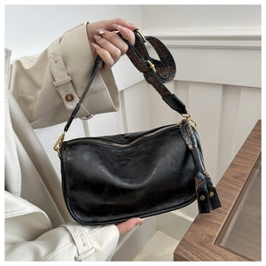 Détail du sac en cuir PU noir avec bandoulière fleurie et pompon décoratif