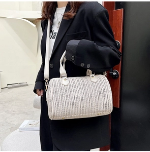 Détail du sac boston tissé crème montrant le cuir synthétique et les ferrures dorées