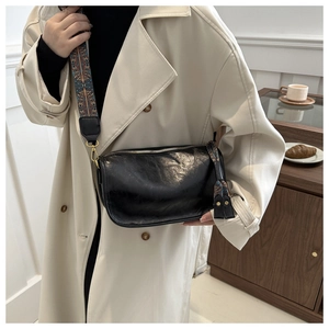 Détail du sac bandoulière en similicuir noir avec large bandoulière à motif géométrique