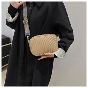 Detail of quilted beige crossbody bag featuring an ethnic patterned wide shoulder strap