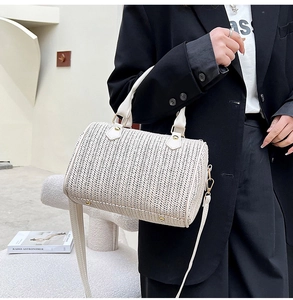 Détail de la texture tissée à chevrons d'un sac Boston crème avec poignées en cuir