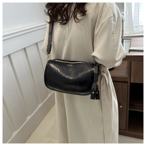 Détail du sac bandoulière cylindrique noir avec large sangle à motif bohème