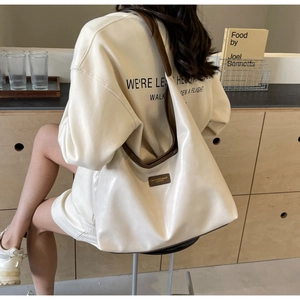 Close-up of cream white PU leather tote bag with dark brown straps and brand label