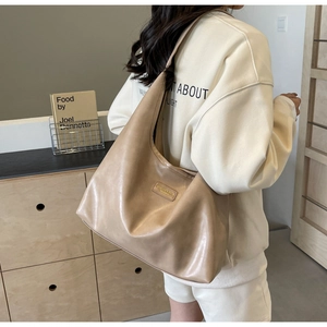 Close-up of beige PU leather hobo bag showing soft pleated texture and rectangular tag