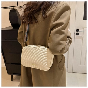 Detail of cream quilted camera bag with wave texture and ethnic style woven strap