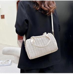 Détail du sac tonneau tissé beige crème sur un blazer noir avec bandoulière réglable